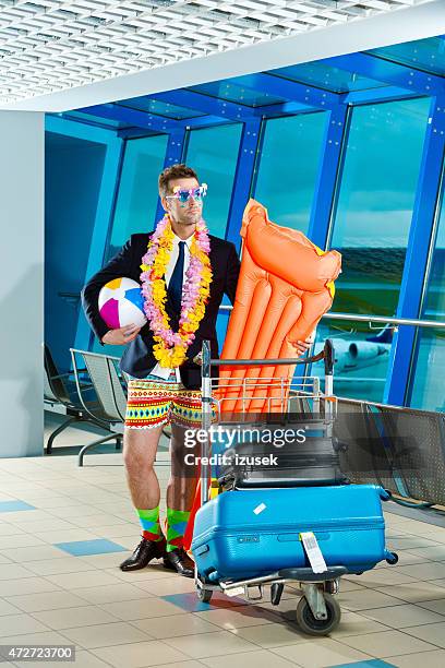 portrait of man wearing beach short and jacket at airport - cartgate out stock pictures, royalty-free photos & images