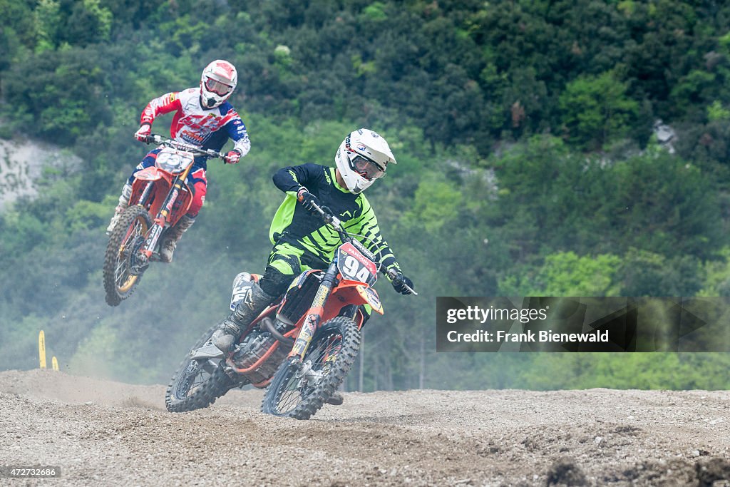 Two motorcyclists on motocross bikes are riding on a dirt...