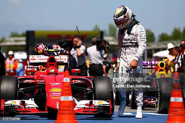Lewis Hamilton of Great Britain and Mercedes GP looks at the car of Kimi Raikkonen of Finland and Ferrari in Parc Ferme after qualifying in second...