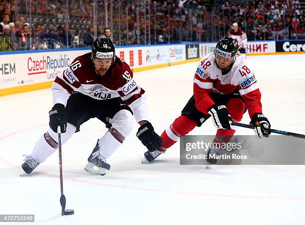 Florian Iberer of Austria and Kaspars Daugavins of Latvia battle for the puck during the IIHF World Championship group A match between Austria and...