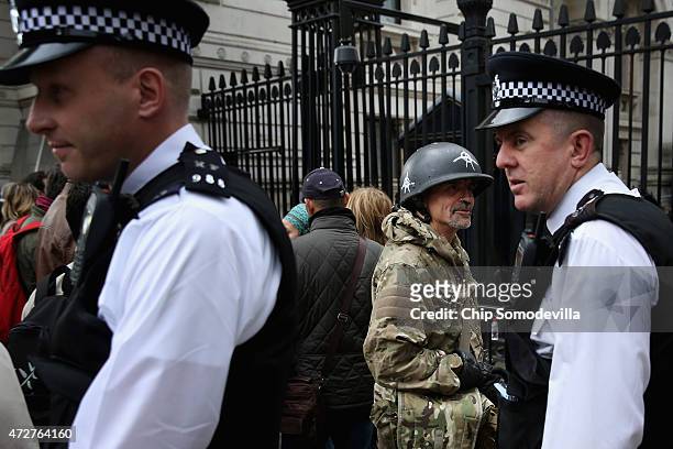 Police leave after talking to a man in military fatigues and a helmet with anarchy symbols outside the security fence protecting Downing Street and...