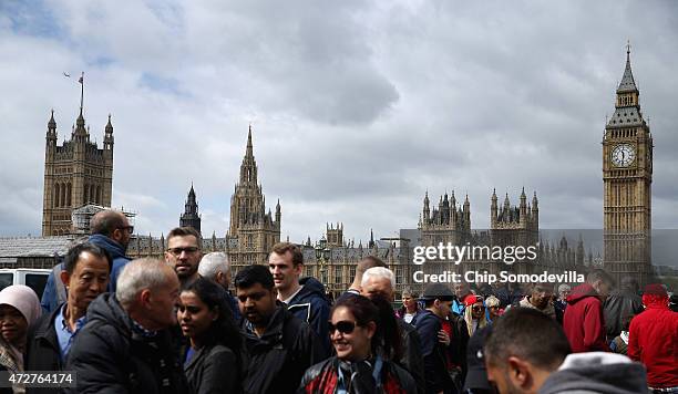 The Houses of Parliament, including Big Ben and The Elizabeth Tower, loom large above the heads of tourists as they cross the Westminster Bridge May...