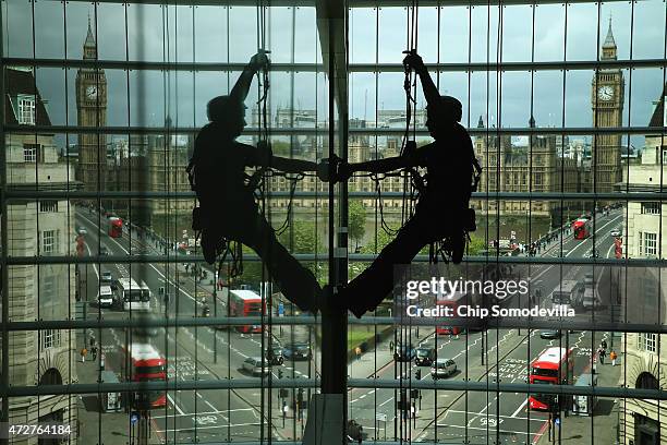 With the Houses of Parliament and the Westminster Bridge in the background, a worker uses climbing rope to scale and repair a wall inside the Park...