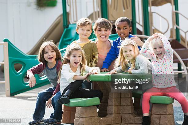 teacher with preschoolers on playground laughing - school yard stock pictures, royalty-free photos & images