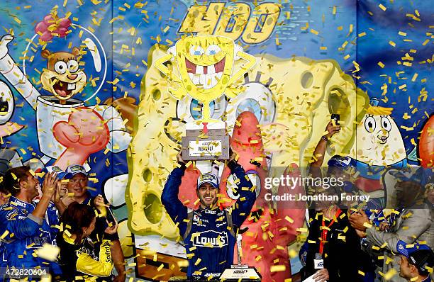 Jimmie Johnson, driver of the Lowe's Chevrolet, celebrates with the trophy in Victory Lane after winning the NASCAR Sprint Cup Series SpongeBob...