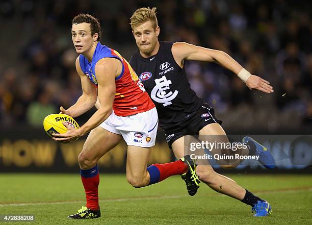 Lewis Taylor of the Lions looks to pass the ball whilst being chased by Nick Graham of the Blues during the round six AFL match between the Carlton...