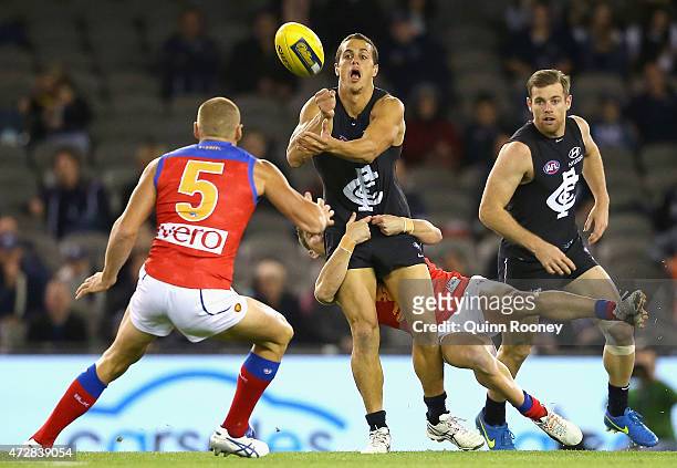 Ed Curnow of the Blues handballs whilst being tackled by Dayne Zorko of the Lions during the round six AFL match between the Carlton Blues and the...