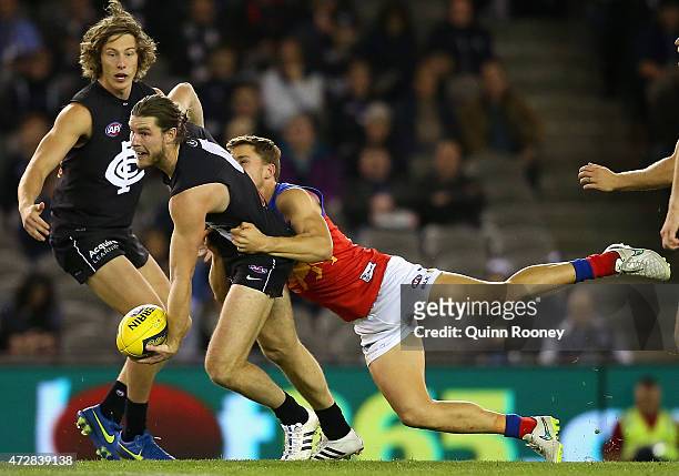 Bryce Gibbs of the Blues handballs whilst being tackled by Jack Redden of the Lions during the round six AFL match between the Carlton Blues and the...