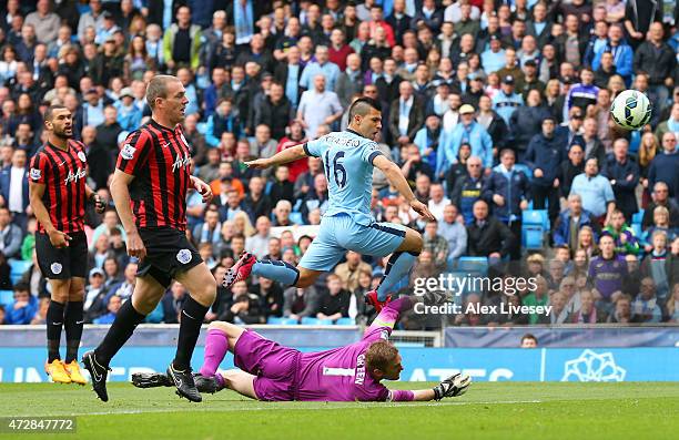 Sergio Aguero of Manchester City lifts the ball over the diving Robert Green of QPR to score the opening goal during the Barclays Premier League...