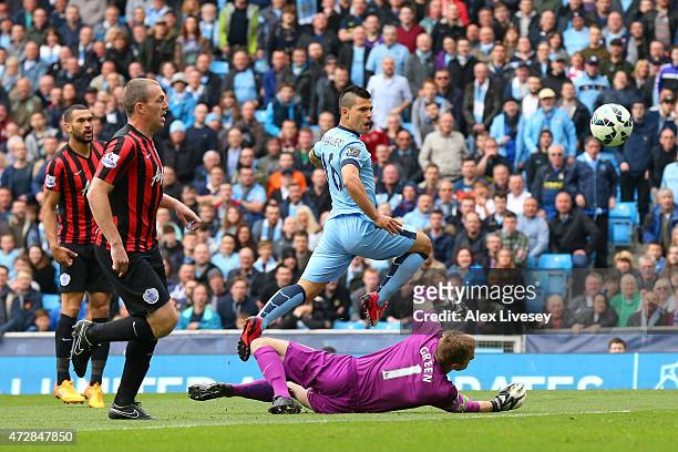 Sergio Aguero of Manchester City lifts the ball over the diving Robert Green of QPR to score the opening goal during the Barclays Premier League...