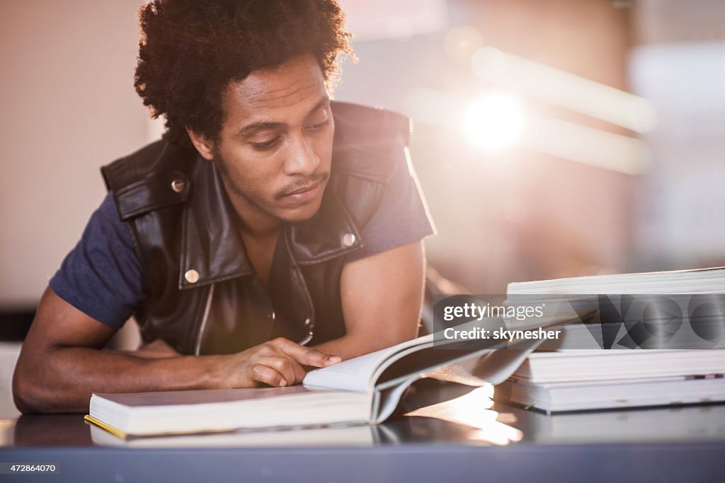 African American young man reading a book and studying.