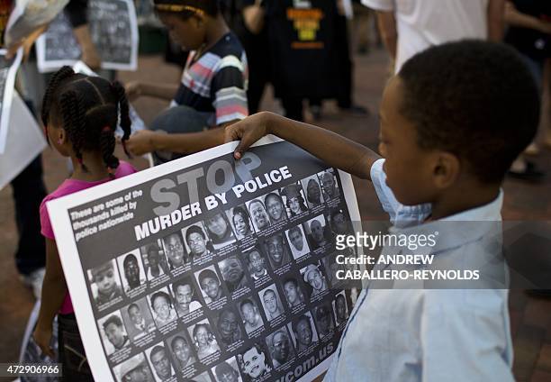 Children look at posters calling for an end to police violence near fans going to a "Rally 4 Peace" concert by Prince in Baltimore, Maryland on May...