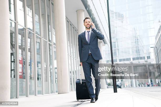 businessman on his cell phone with suitcase - bringing home the bacon engelse uitdrukking stockfoto's en -beelden