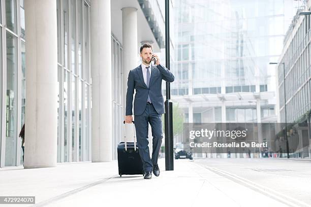 businessman on his cell phone with suitcase - bringing home the bacon engelse uitdrukking stockfoto's en -beelden