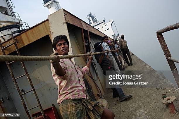 Group of men pulling some rope on top of a mega ship that has been abandoned to be disassembled on Chittagong beach. Where do the mega freighters and...