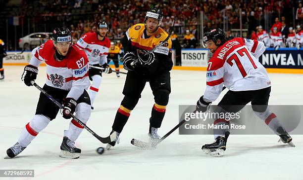 Daniel Pietta of Germany and Konstantin Komarek and Florian Muhlstein of Austria battle for the puck during the IIHF World Championship group A match...