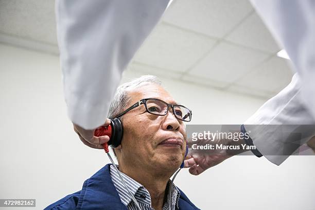 Doctor Ivan T.J. Wu, an audiologist, places headphones on Chin Yin Chiu's for a hearing test during the Hsi Lai Temple Health Fair, in Hacienda...