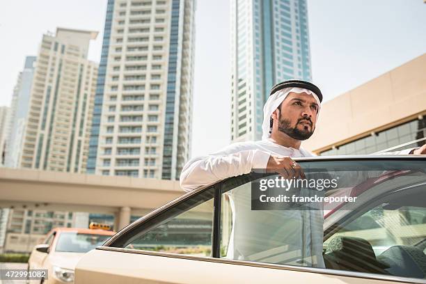 arabo sceicco in piedi fuori del taxi - dubai taxi foto e immagini stock