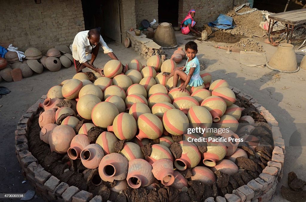 A potter puts the earthen pitcher on a Bhatti before selling...