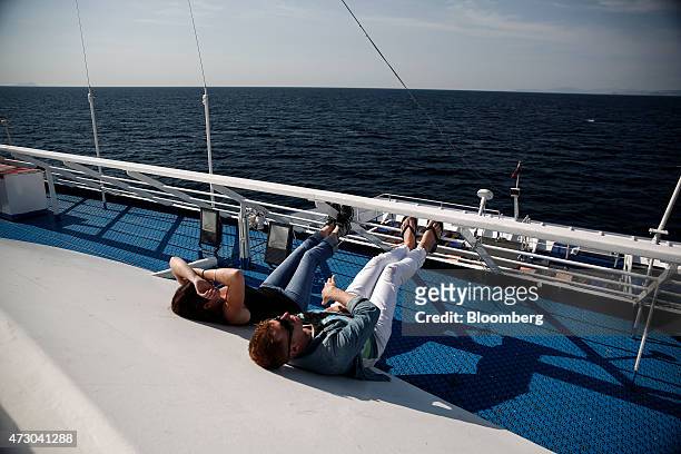 Tourists lie in the sun aboard a cruise ship sailing in the Saronic gulf west of Athens, Greece, on Monday, May 11, 2015. Less than three weeks after...