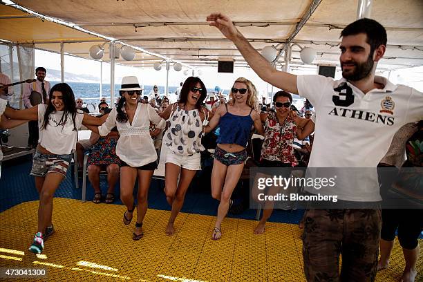 Dance teacher instructs tourists in the art of Syrtaki dance aboard a cruise ship sailing in the Saronic gulf west of Athens, Greece, on Monday, May...