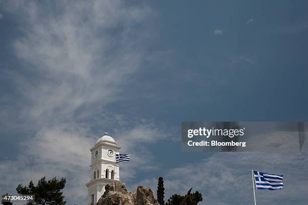 Greek national flags flie from flag poles on the island of Poros, Greece, on Monday, May 11, 2015. Less than three weeks after a Greek aid meeting...