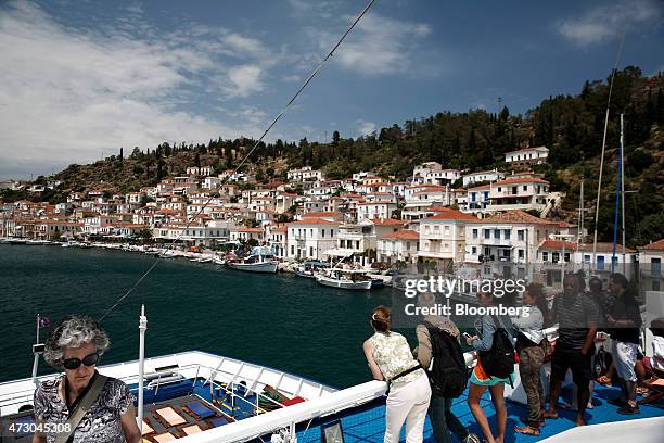 Tourists stand on the deck of a cruise ship as it arrives at the island of Poros, Greece, on Monday, May 11, 2015. Less than three weeks after a...