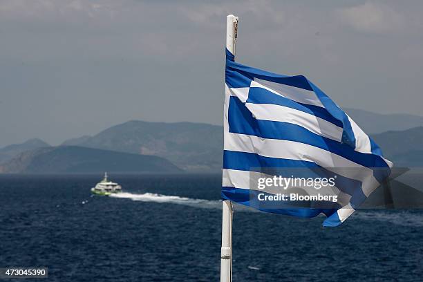 Hyrdofoil passenger ferry sails past a Greek national flag as it leaves the port in Hydra, Greece, on Monday, May 11, 2015. Less than three weeks...