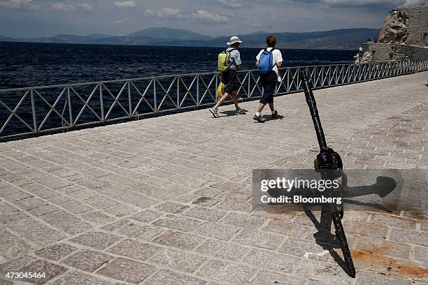 Tourists walk along the promenade during a visit to the island of Hydra, Greece, on Monday, May 11, 2015. Less than three weeks after a Greek aid...