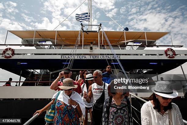 Tourists disembark from a cruise ship on the island of Poros, Greece, on Monday, May 11, 2015. Less than three weeks after a Greek aid meeting broke...