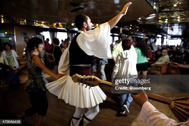 Dancer wearing traditional Greek costume performs a dance with tourists aboard a cruise ship sailing west of Athens, Greece, on Monday, May 11, 2015....