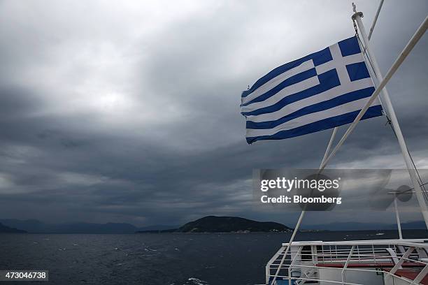 Greek national flag flies from a cruise ship as it approaches the island of Aegina, Greece, on Monday, May 11, 2015. Less than three weeks after a...