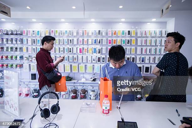 Customers look at Xiaomi phones during the first day of the high configuration Xiaomi Note to be on sale at a Xiaomi experience store on May 12, 2105...