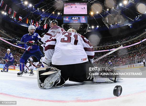 The puck passes goalkeeper Edgars Masalskis of Latvia into the goal after a shot by the team of France during the group A preliminary round match...