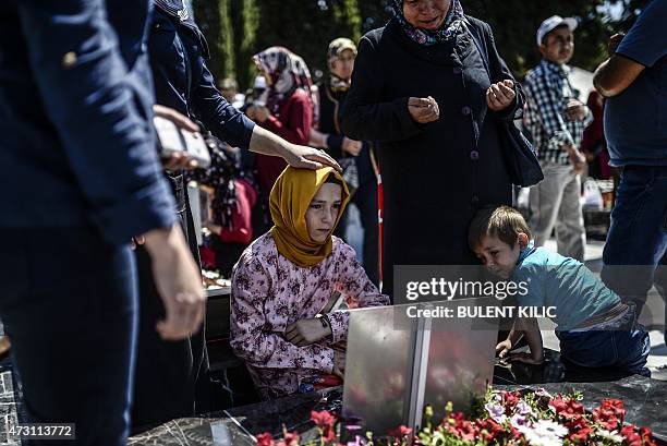 Young woman sits at by a grave as relatives and friends gather at the cemetery in the Turkish town of Soma in the Manisa district, western Turkey, on...