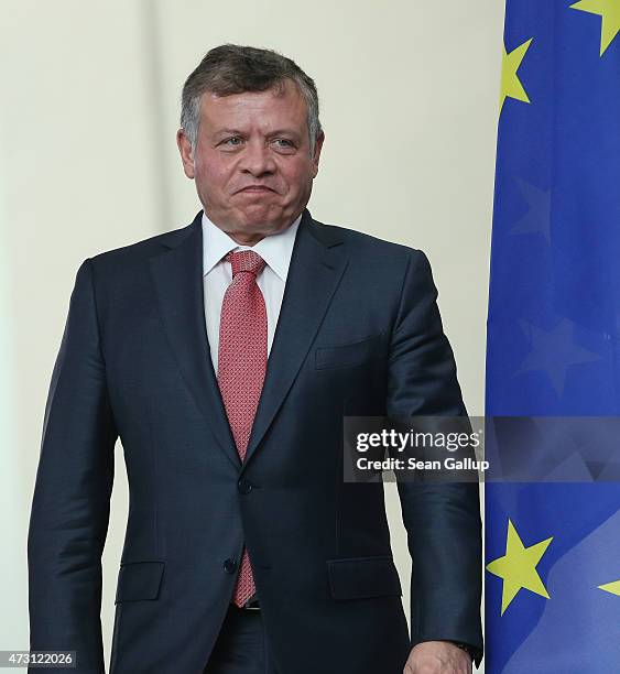 King Abdullah II of Jordan walks past the flag of the European Union as he arrives to speak to the media with German Chancellor Angela Merkel...