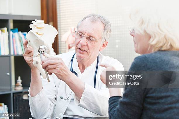 mature medicine presenting total hip arthroplasty to female patient - hips stock pictures, royalty-free photos & images