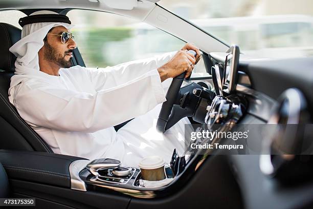 middle eastern man driving a luxury car in dubai - arab lifestyle stockfoto's en -beelden