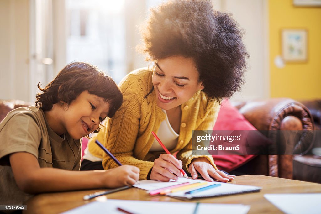 Smiling African American mother and son coloring together.