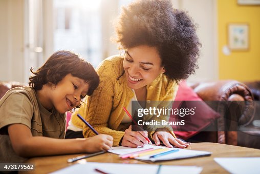 Smiling African American mother and son coloring together. Smiling African American mother and son coloring together.