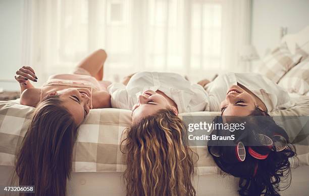young smiling women relaxing together in bed and communicating. - girls' night in stock pictures, royalty-free photos & images