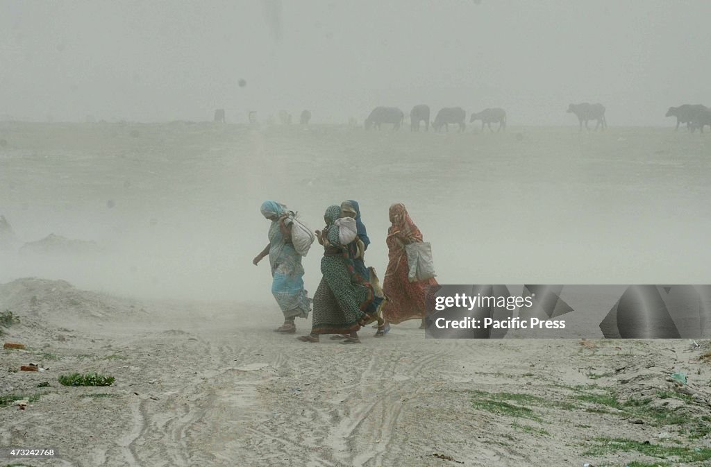 Devotees walk trough dust storm at Sangam, the confluence of...