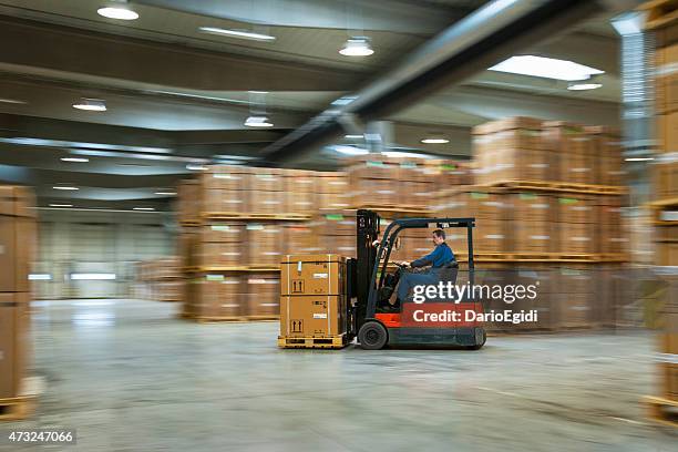 worker on a lift truck arranging boxes in industrial warehouse - forklift 個照片及圖片檔