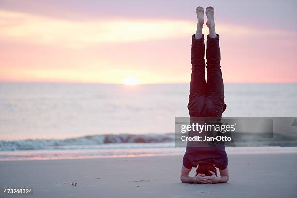 male guy doing headstand at the beach of st.peter-ording, germany - handstand stock pictures, royalty-free photos & images