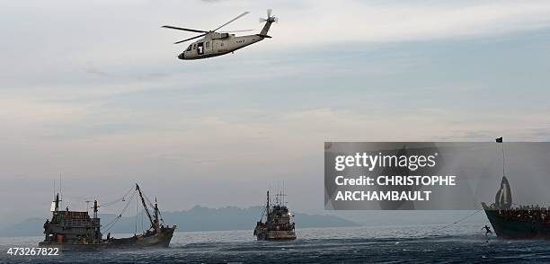 Rohingya migrants jump to collect food supplies dropped by a Thai army helicopter, from a boat drifting in Thai waters off the southern island of Koh...