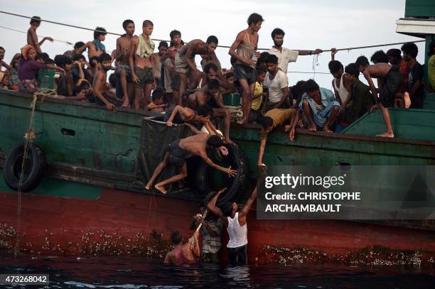 Rohingya migrants pass food supplies dropped by a Thai army helicopter to others aboard a boat drifting in Thai waters off the southern island of Koh...