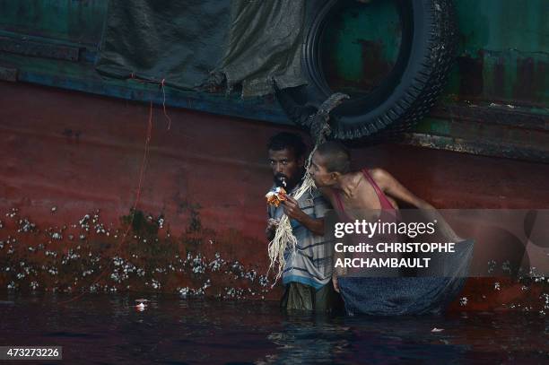 Rohingya migrant eats food dropped by a Thai army helicopter after he jumped to collect the supplies at sea from a boat drifting in Thai waters off...