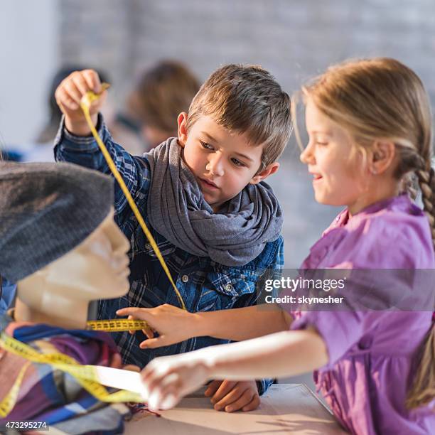 creative little girl and boy measuring mannequin in design studio. - boy-mannequin stock pictures, royalty-free photos & images