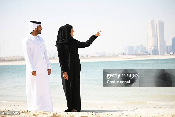arabische paar in traditioneller kleidung am strand - muslim woman beach stock-fotos und bilder