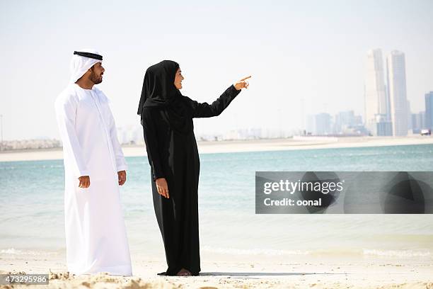 arab couple with traditional wear on the beach - muslim woman beach stock pictures, royalty-free photos & images